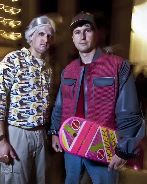 A couple of men standing next to each other holding a skateboard